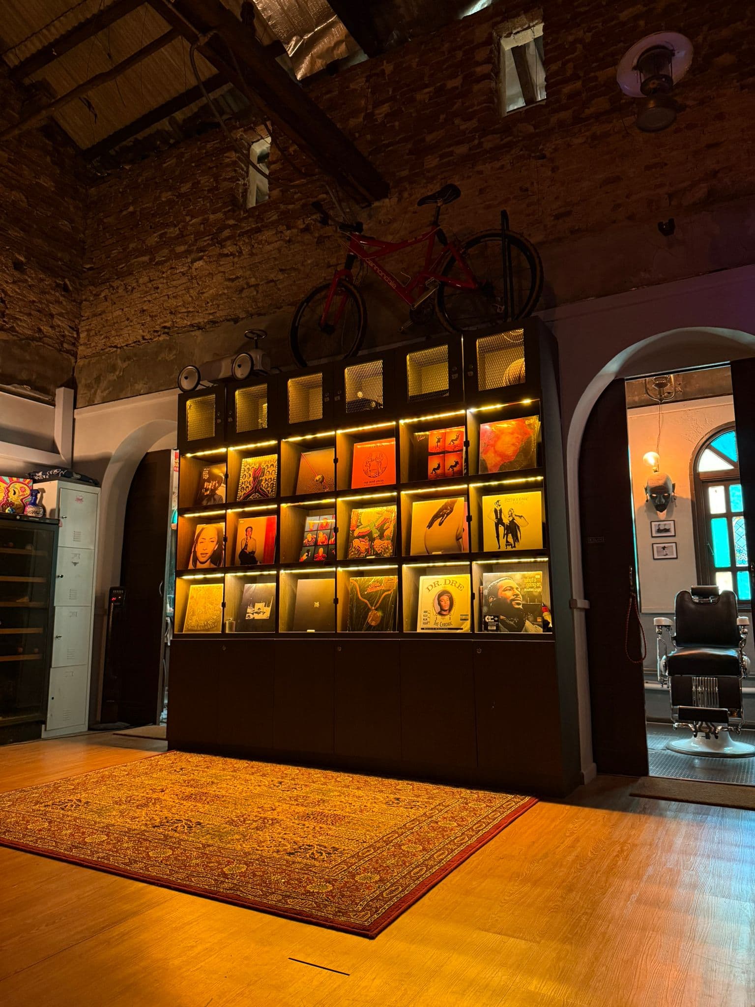 Lit vinyl record wall beside the barbershop entrance at Cult Commons